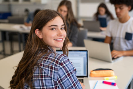 High school student smiling facing camera using laptop